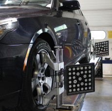 Black car with its wheels being fixed in a repair service station