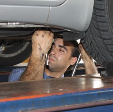 A mechanic working under a lifted car at a repair service station