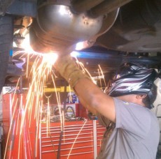 A mechanic welding under a lifted car at a repair service station